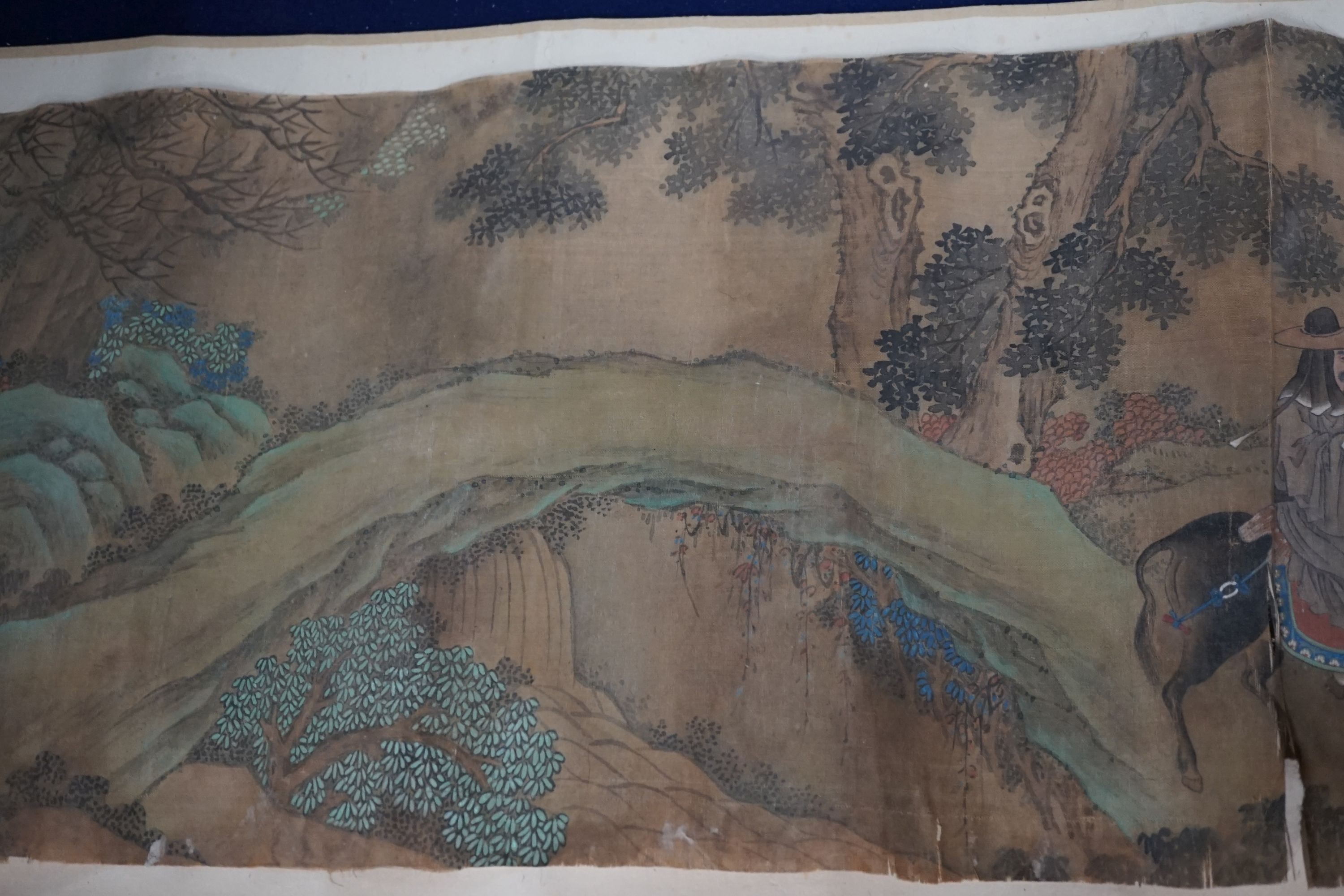 A 19th century Chinese hand scroll painting on silk of figures in a landscape, approximately 206 cm X 32.5 cm